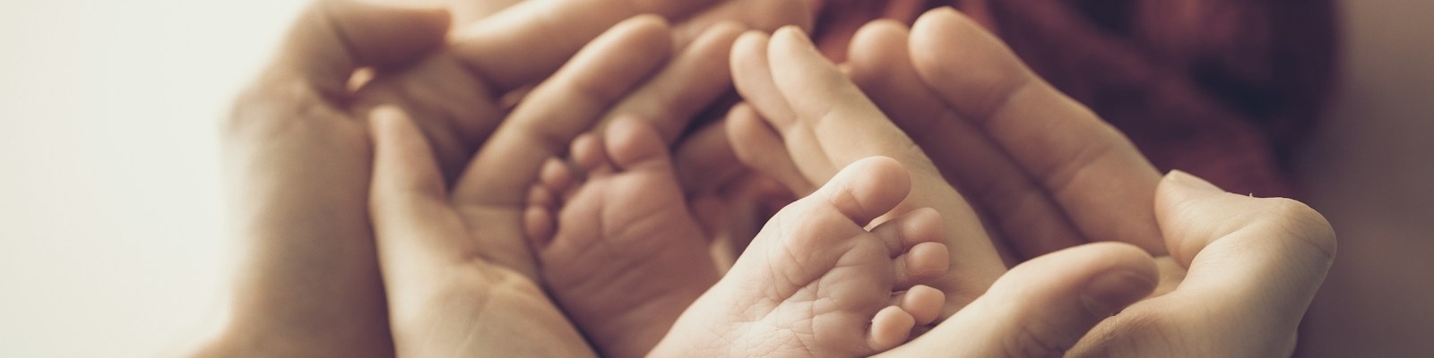 Parent's hands gently holding newborn baby's feet